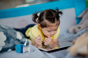 asian children watching tablet  / playing phone and looking at cartoon / kid play tablet