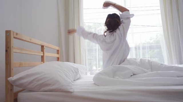 Young asian woman wake up in the morning and sitting on bed at mirror door side relaxing in holiday with sunlight, Vintage 
