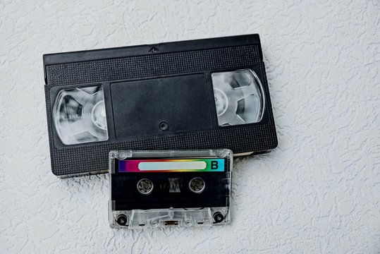 кассета аудио и чёрная видеокассета на сером столе