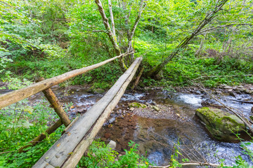 small wooden bridge across a rushing mountain river