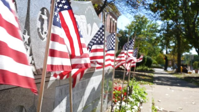American flags blowing in small american town near war monument