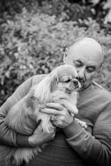 Mature man on a walk with his little friend little red dog pekingese. Senior dog lover and pet