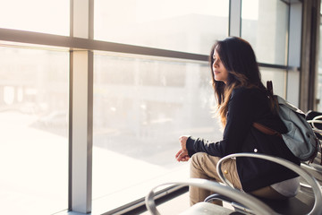 Young woman waiting for plane at airport lounge