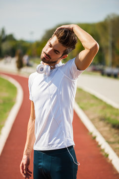 Young man is exercising on sunny day. He is stretching his body.