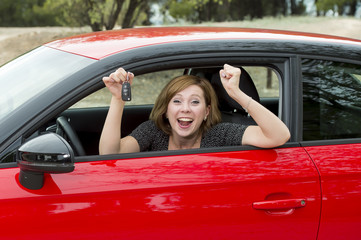 attractive woman smiling proud sitting at driver seat holding and showing car key in new automobile buying and renting