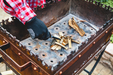 gloved hand kindles fire in grill with long lighter