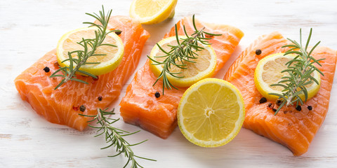 Raw salmon pieces on wooden board with herbs, salt and spices