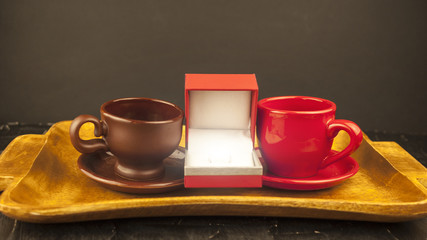 A small box with a ring between two cups of the concept of love