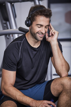 Gym guy lost in music with headphones in gym, smiling
