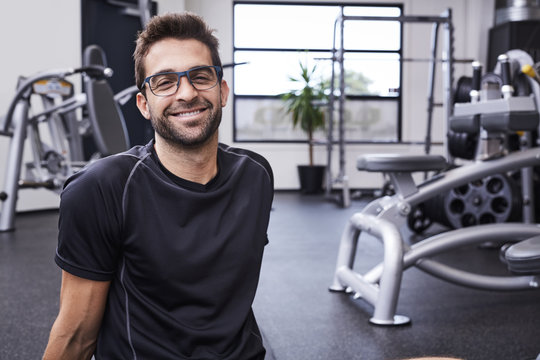 Athletic glasses guy smiling in gym, portrait