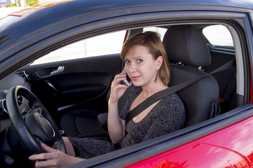 Fototapeta na wymiar woman talking happy on mobile phone while holding car steering wheel driving distracted