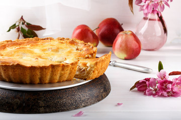 Homemade creamy apple pie on white wooden table.