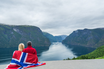 Couple with the flag of Norway looks at the fjord