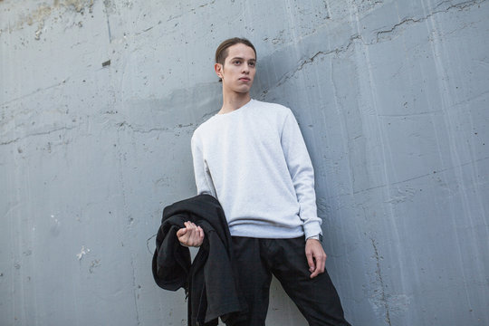 Young Man In Gray Sweatshirt On Grey Background. Mock-up.