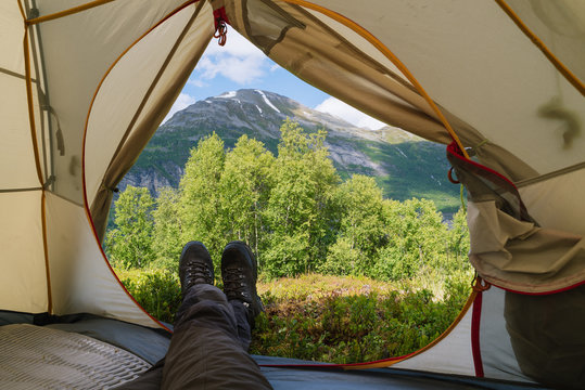 Guy is looking from the tent to the mountains