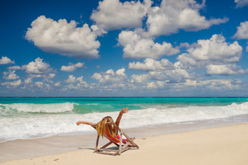 Obraz na płótnie Canvas Woman sitting on a chair at the beach