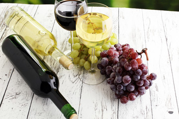White wine and red wine in a glass with fall grapes, white wooden background