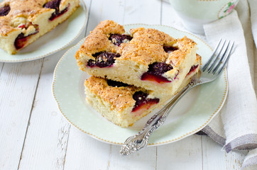 Plum cake with caramel on a white wooden table