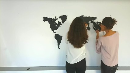 Girls twins fixing the world map on the wall. Fast speed time lapse - Powered by Adobe