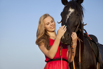 Obraz premium Smiling blonde stroking a horse. Portrait of a young woman with a stallion
