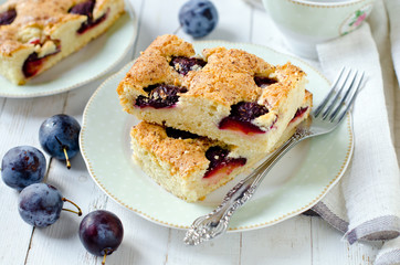 Plum cake with caramel on a white wooden table