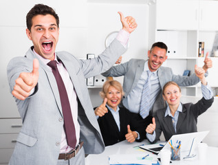 Excited businessman with happy team celebrating victory