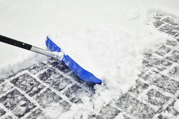 Motion blurry blue colored snow shovel in action.