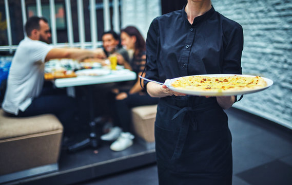 Waiters carrying plates with food, in a restaurant.