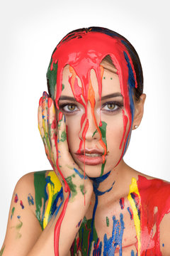Colours paint dripping down on face. Beauty fashion art portrait of beautiful woman with colorful abstract makeup. White background