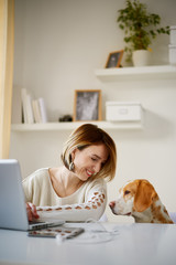 Caucasian woman working at home office while her dog watching her/  businesswoman in thirties...