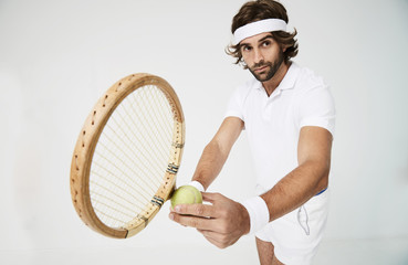Serious tennis guy ready to serve in studio, looking away