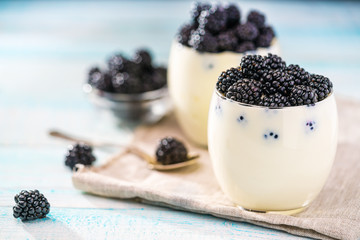 Fototapeta na wymiar Berries of fresh blackberry and yogurt on a wooden background
