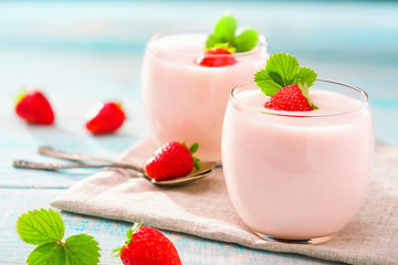 Two glasses of pink yogurt on a wooden background