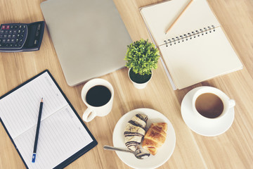 Top view of team meeting showing cup of coffee ,notebook, laptop on wooden table.