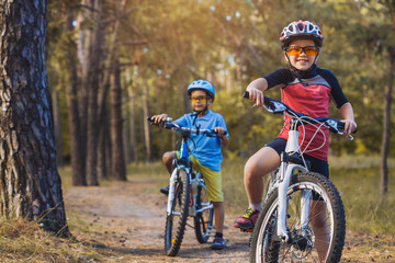 kids on abicycles in the sunny forest. children cycling outdoors in helmet
