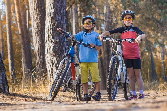 kids on abicycles in the sunny forest. children cycling outdoors in helmet
