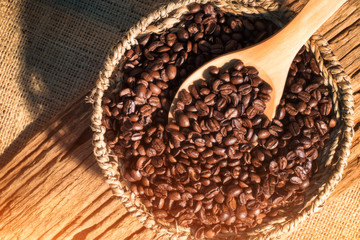 Coffee beans on wooden spoon over basket of coffee beans background.Matte style,vintage style.