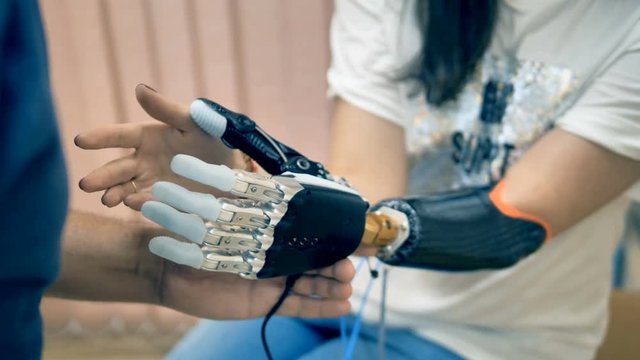 Young woman trying wireless bionic prosthesis. 4K.