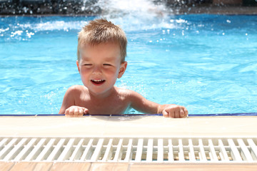 Happy smiling boy swimming in the pool on a sunny day