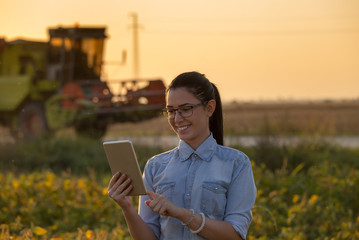 Farmer girl with tablet and combine harvester