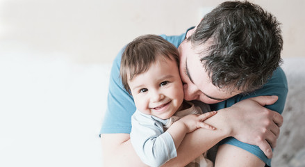Close-up portrait of happy young father hugging and kissing his sweet adorable child.