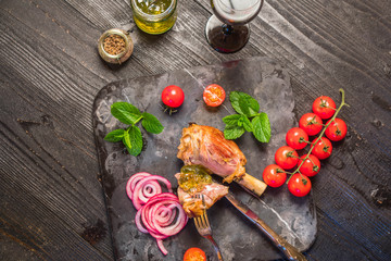 Lamb shank dinner, with vegetables, parsley, mint jam and red wine on black rustic wooden table, top view, copy space