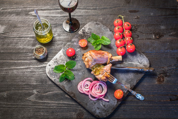 Lamb shank dinner, with vegetables, parsley, mint jam and red wine on black rustic wooden table, top view, copy space