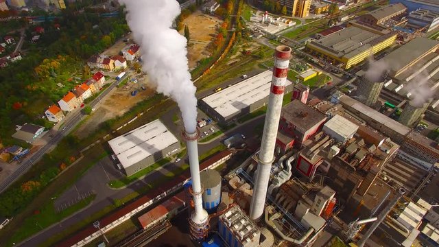 Camera flight over a modern combined heat and power plant. Fuming chimney with sulphur removal unit. Heavy industry from above. Power and fuel generation in European Union. 