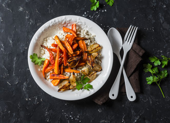 Pearl barley with caramelized baked carrots and onions. Autumn vegetarian buddha bowl. On a dark background, top view