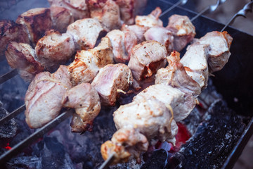 Grilled kebab cooking on metal skewers (grill). Roasted meat cooked at barbecue with smoke. Close up BBQ fresh pork meat chop slices. Traditional eastern dish, shish kebab.