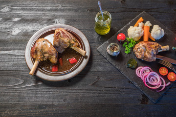 Lamb shank dinner, with vegetables, parsley and mint jam on black rustic wooden table, top view, copy space