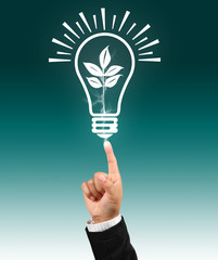 Bulb light with leaf on businessman fingertip