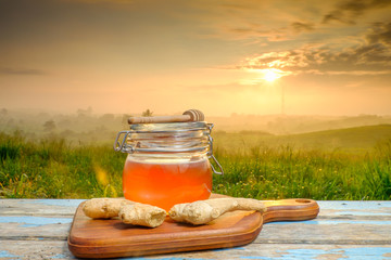Alternative Medicine with garlic and  honey on wooden table. Beautiful sunrise as background.