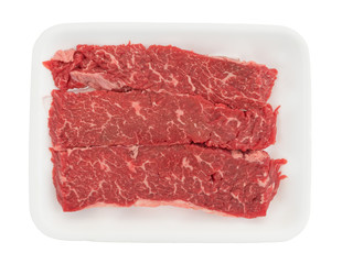 Top view of raw beef loin sirloin grilling tips on a foam butcher tray isolated on a white background.